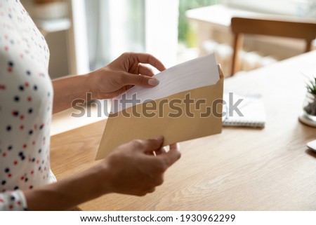 Postal correspondence. Close up view of young woman open paper letter message document prepare to read news view information. Female hands put written note in envelop before send it by mail to friend Royalty-Free Stock Photo #1930962299