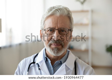 Headshot portrait of mature Caucasian male doctor in glasses wear white medical uniform look at camera in hospital. Profile picture of senior man GP or therapist pose in clinic. Healthcare concept.