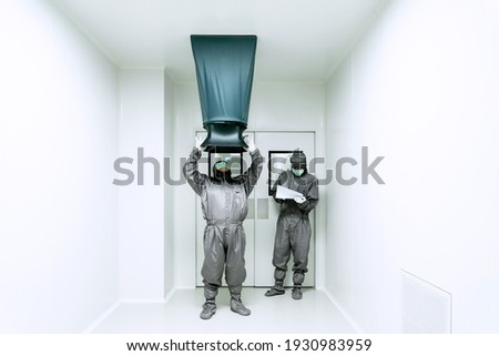 Two unidentified operators are using the capture hood balometer to measuring the air velocity and volume of supply air from HVAC system in the cleanroom. Royalty-Free Stock Photo #1930983959