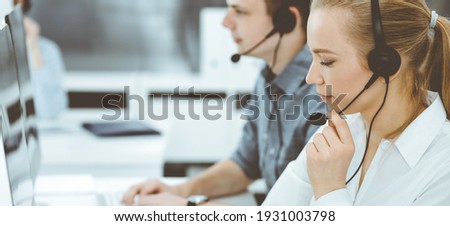 Call center. Group of casual dressed operators at work. Blond business woman in headset at customer service office. Telesales in business Royalty-Free Stock Photo #1931003798