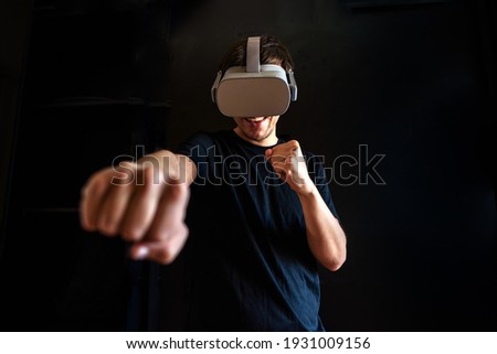 Gamer boy using virtual reality glasses having fun at home and playing video game.