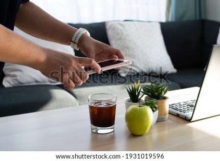 Diet woman with smartwatch using smartphone to take picture of green apple and black iced tea via counting calories application on smartphone to control her calories intake per day.Modern life style 
