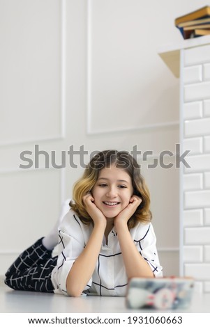 teenage girl smiling lying on the floor and watching online broadcast in smartphone, online training