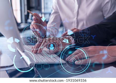 Two information technology specialist brainstorming on project to create a new approach to develop software to improve business service. Working with laptop. Tech hologram icons. Formal wear.