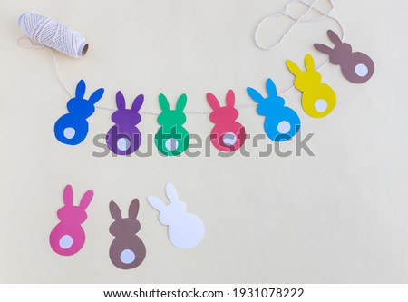 garland of Easter bunnies made of colored paper on a light background
