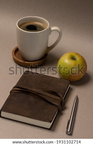 coffee and notebook and apple o gray background with lights 