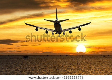rear image commercial passenger aircraft or cargo transportation airplane fly over coast of sea after takeoff from airport in evening with sun and golden sunset seascape view Royalty-Free Stock Photo #1931118776
