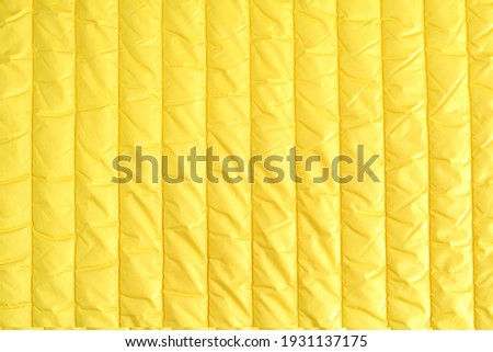 Factory quilted fabric in fashionable yellow color. Abstract background.