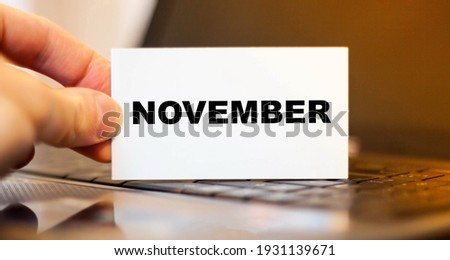 A man holds a business card with the name of the month - November