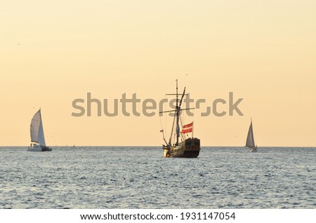 18th century sailing yacht and modern sailboats in an open sea at sunset. Holland. Old tall ship. Recreation, vacations, cruise, historical reenactment, past, history, regatta, transportation