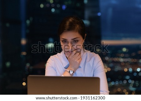 Close up thoughtful Indian businesswoman using laptop at late hours, finishing, working on project at night, touching chin, looking at computer screen, pondering, solving problem, deadline concept Royalty-Free Stock Photo #1931162300