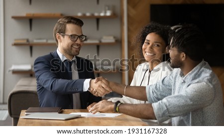 Close up smiling manager and African American family shaking hands, making successful investment or insurance deal, overjoyed young couple and realtor broker handshaking, taking loan or mortgage Royalty-Free Stock Photo #1931167328