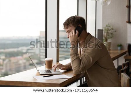 Close up confident businessman talking on phone, using laptop, looking at screen, entrepreneur manager consulting client by call, looking at computer screen, discussing project, reading information Royalty-Free Stock Photo #1931168594