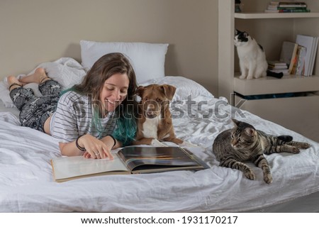 tennager with a book and pet on the bed in a bedroom Royalty-Free Stock Photo #1931170217