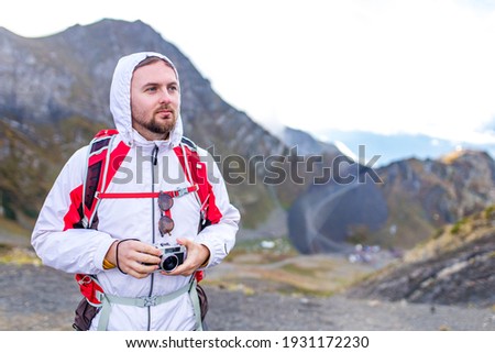 Young cheerful man photographer taking photographs with old school vintage camera in a mountains
