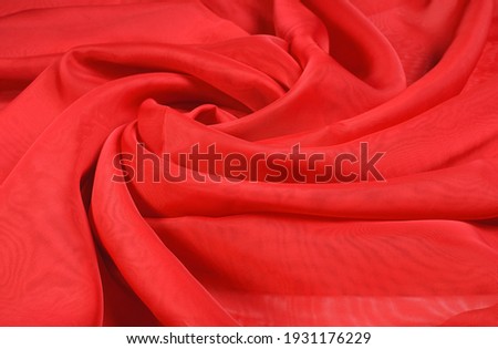 Abstract background of swirling, light, wavy, red, chiffon fabric in the shape of a rose, Fabric background for cosmetics, perfume, cream