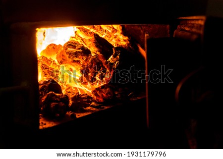 Embers in a coal furnace. Red coals from high temperature. The oven door is open. Heating the house with coal. Non-ecological fuel.