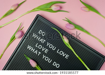 Do what you Love. Love what you do - motivational quote text on black letter board on pink background with tulips. Pastel colors, soft image.  Flat lay