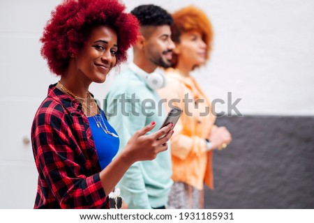 Several modern young people walking looking at the mobile phone and looking at camera - freestyle concept