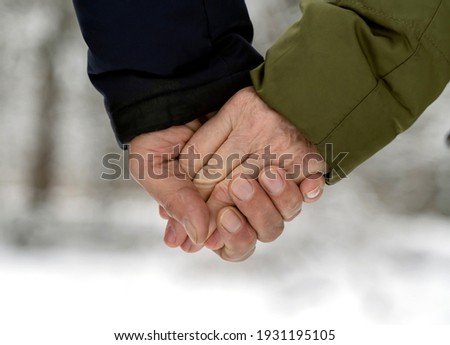 elderly couple hold hands on a walk in the winter