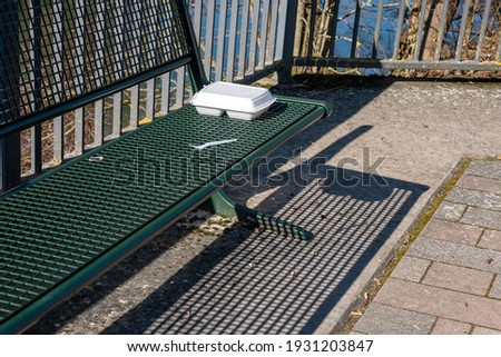 Plastic food packaging left on park bench outdoors plastic fork left behind thrown away abandoned trash left behind