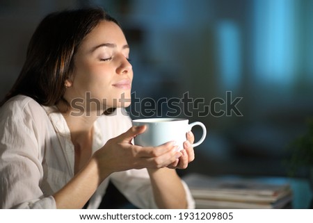 Relaxed woman smelling decaffeinated coffee in the night at home Royalty-Free Stock Photo #1931209805