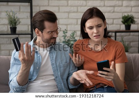 Worried annoyed young husband wife using phone credit card dissatisfied with interrupted wifi internet connection slow bad app work. Angry family couple bank clients unable to pay online check balance Royalty-Free Stock Photo #1931218724