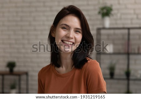 Headshot portrait profile picture of cheerful teen female posing at home with adorable white hollywood smile. Laughing young lady looking at camera webcam enjoy pleasant talk by videocall in good mood