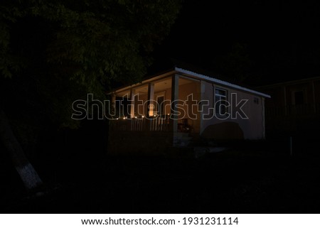 Old house with a Ghost in the forest at night or Abandoned Haunted Horror House. Old mystic building in dead tree forest. Surreal lights. Horror Halloween concept