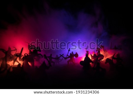 Medieval battle scene. Silhouettes of figures as separate objects, fight between warriors at night. Creative artwork decoration. Foggy background. Selective focus Royalty-Free Stock Photo #1931234306