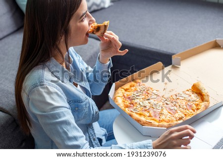 Portrait of a young woman eating pizza.
