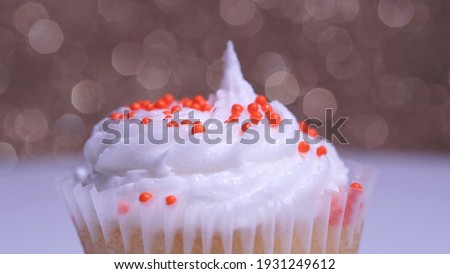 Decorated colourful cupcake for the holiday, shallow depth of field. Close up macro focus on the iced muffin. Gold background. Presentation of delicious desserts at anniversary or birthday.