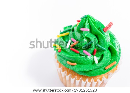 St. Patrick's Day green frosted vanilla cupcakes with rainbow sprinkles on a white background