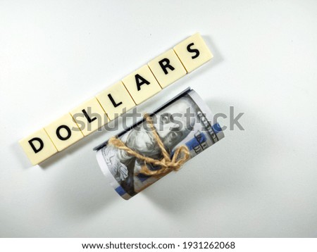Selective focus.Dollar banknotes and scrabble letters with text DOLLARS on white background.Business concept.