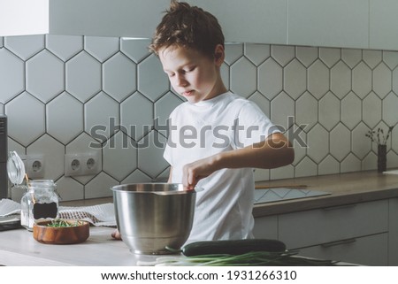 Boy 7-10 whips omelet with whisk. Son doing household chores. Royalty-Free Stock Photo #1931266310