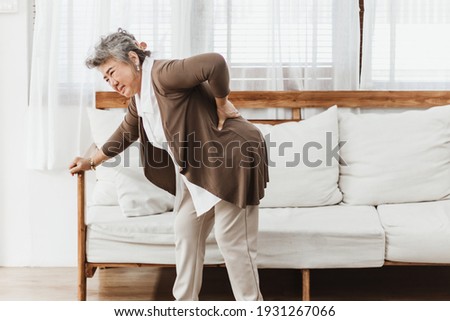 Asian senior woman pain from backache alone at home. Elderly woman pain and hurt from osteoporosis sickness or back injury. Old adult life insurance with health care and treatment concept Royalty-Free Stock Photo #1931267066
