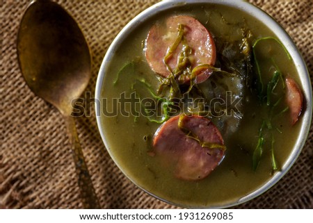 green broth with pepperoni and cabbage top view on rustic wooden table with selective focus and golden spoon 
