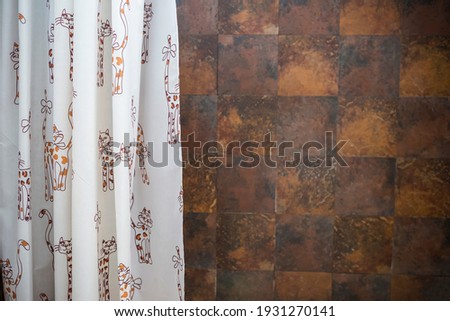 Shower curtain with cat cartoon pattern over blurred brown tile texture backgrund, interior design, bathroom design