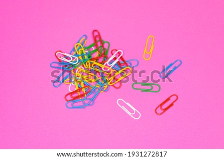 Paper clips of various colors on pink colored paper Royalty-Free Stock Photo #1931272817