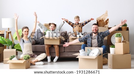 Delighted parents and cute kids with raised arms gathering on sofa in living room with unpacked boxes,   looking at camera and enjoying relocation in new flat Royalty-Free Stock Photo #1931286671