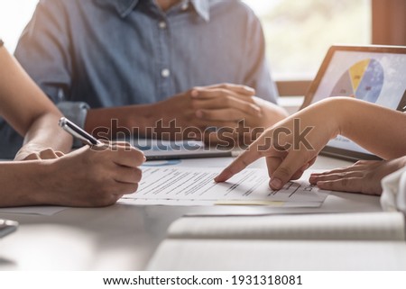 financial investor advisory.  Close up hand pointing at contract and document while sitting together with young couple at the desk in office Royalty-Free Stock Photo #1931318081