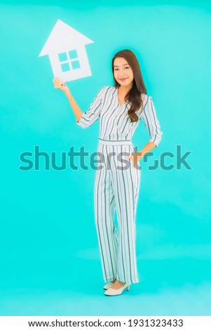 Portrait beautiful young asian woman show home or house sign on blue background