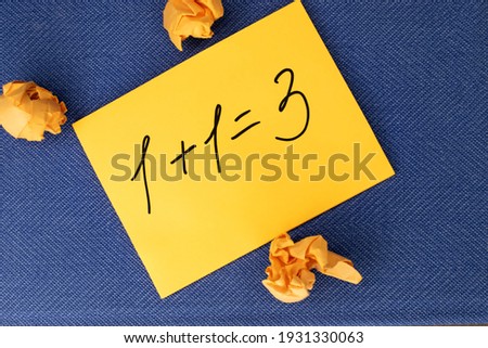 An incorrectly solved mathematical example is written on a yellow piece of paper which lies on a blue background near the crumpled sheets of paper