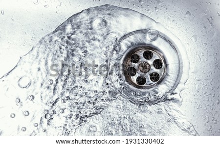 water drain down on stainless steel kitchen sink hole. top view sewer in washbasin. household plumbing. cleaning and hygiene concept. Royalty-Free Stock Photo #1931330402