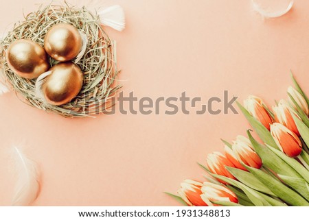Easter Golden colour eggs in basket with spring tulips, white feathers on pastel pink background in Happy Easter decoration. Festive decoration in flat lay