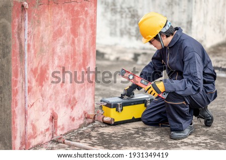 Male Asian mechanic or maintenance worker man wearing protective suit and helmet opening work tool box at construction site. Equipment for mechanical engineering project