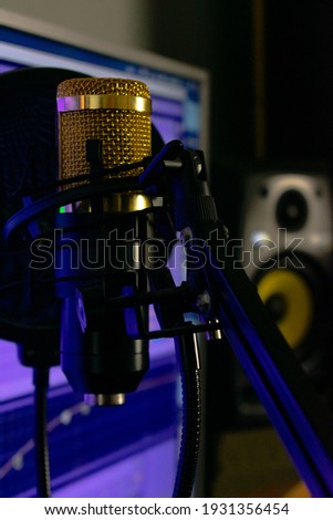 A gold microphone in front at the camera, besides a production program and a horn at the background