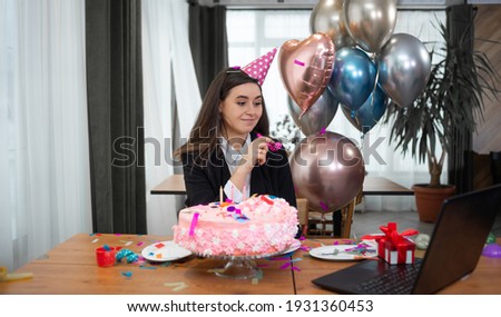 portrait of a young beautiful caucasian woman sitting at a table and celebrating her birthday. communicates via laptop webcam. Copy space.