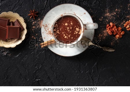 Hot chocolate with cinnamon, nuts, and copy space, shot from above on a black background