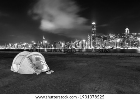 People camping on seaside promenade of Victoria harbor in Hong Kong city at night